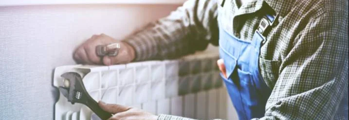 Person repariert Heizung mit Schraubenschlüssel